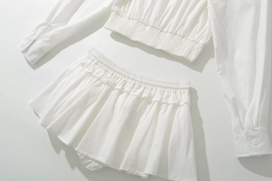 Detailed macro of white cotton shirt and ruffled skirt set with elastic smocked textures