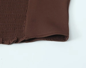 Detailed macro shot of the smocked elastic fabric and ruffle hem on the brown camisole