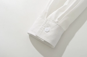 Detailed close-up of white shirt sleeve cuffs with neat pleats and a resin button