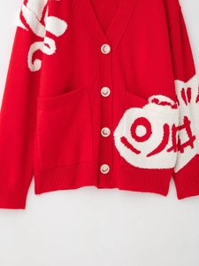 Detail of red knit cardigan featuring white jacquard patterns and large front pockets