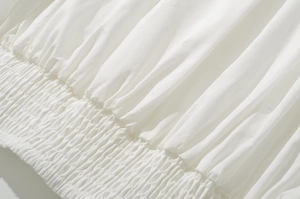 Detailed macro view of white smocked fabric with delicate elastic gathers and texture