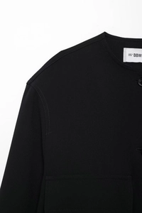Detail view of black cotton jacket featuring round neck, dropped shoulders, and button