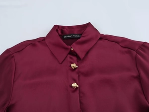 Detail of satin shirt with gold buttons, burgundy silk texture and collar label focus