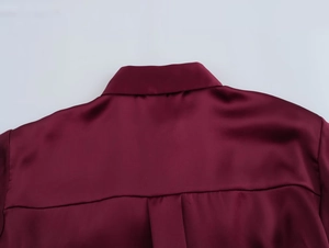 Detailed macro shot of burgundy satin blouse collar and shoulder stitching texture