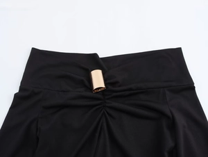 Close-up of black elastic fabric waist with a polished gold decorative buckle detail