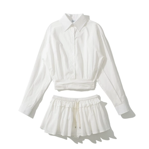 Women's white two-piece set featuring long sleeve button-up shirt and pleated drawstring skirt