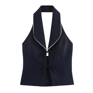 Detail of navy blue halter top featuring white contrast trim and front bow tie closure