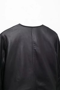 Close-up of black leather jacket back seam and round collar detail on white background