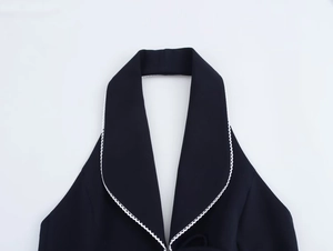 Close-up of black halter neck top with white wavy lace trim on the blazer collar