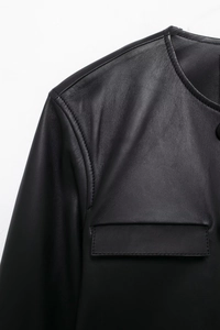 Close-up of black leather jacket shoulder seams and chest pocket flap with topstitching