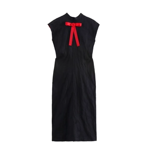 Détail d'une robe noire sans manches avec col montant et nœud de rose rouge