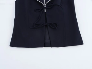 Detail of navy sleeveless top featuring front bow ties and white scalloped lace trim