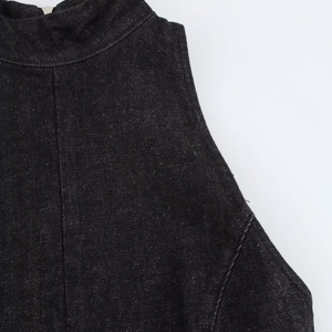 Détail de mini-robe en jean noir montrant le col haut et le zip métallique au dos