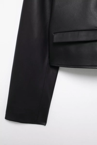 Close-up detail of premium black leather jacket showing fine stitching and pocket texture