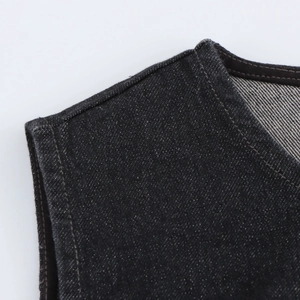 Détail rapproché de la texture du denim foncé et des coutures précises sur l'encolure sans manches