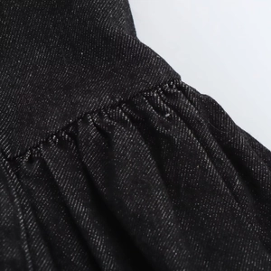 Détail du tissu denim noir montrant les coutures froncées et la texture sergé de qualité