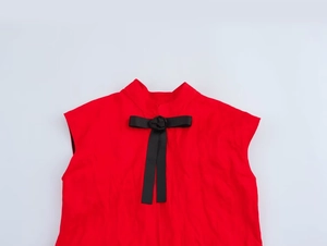 Détail de robe rouge à col montant avec nœud noir et décoration de rose en relief