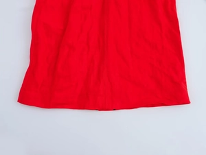 Gros plan de l'ourlet de la robe rouge montrant la texture plissée et les coutures