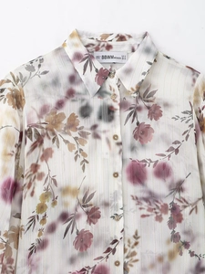Gros plan sur une chemise blanche imprimée avec fils dorés et motifs floraux fins