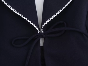 Detail of the V-neckline with white lace trim and bow tie on the dark woven top