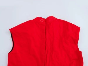 Détail d'un haut rouge sans manches avec surpiqûres blanches en forme d'étoile