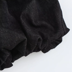 Gros plan détaillé des poignets élastiques froncés sur une robe en sergé noir