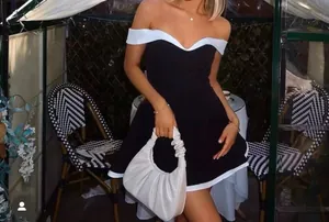 Close-up of a stylish black and white off-shoulder mini dress with chic white piping details