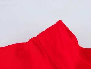 Détail du décolleté en tissu rouge avec des coutures soignées sur matière lisse