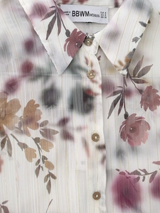 Détail d'une chemise à fleurs légère avec rayures dorées et boutons marron