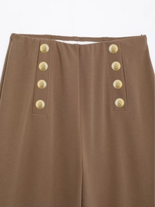 Close-up of high-waisted brown wide-leg trousers featuring golden embossed double-breasted buttons