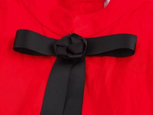 Détail d'une robe rouge ornée d'un nœud en ruban gros-grain noir avec rosette centrale