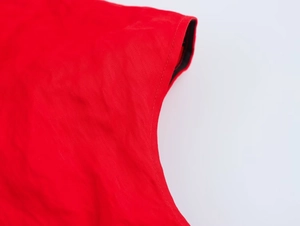 Détail de la robe rouge montrant les doubles coutures et la texture du tissu en coton premium