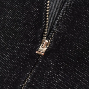 Vue macro d'une fermeture éclair en métal et de la texture du denim sur une robe chic