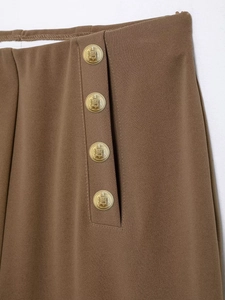 Detail of high waist trousers with golden embossed heraldic buttons and twill fabric