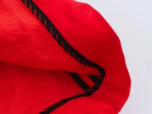 Détail macro du tissu rouge avec bordure en ruban noir et couture en zigzag précise