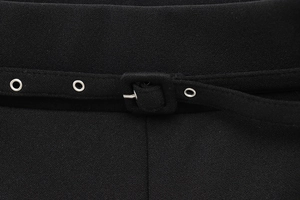 Detail of high-waist black wide-leg trousers with a thin belt and silver eyelets