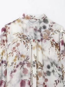 Détail d'une blouse en mousseline fleurie avec rayures métalliques et pli creux au dos