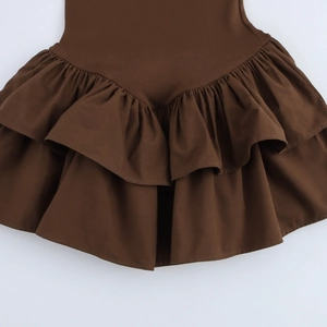 Detail of deep brown dress featuring double-layered ruffle hem and pleated design