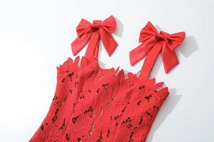 Close-up of red lace dress detailing red satin bow straps and silver metal rings