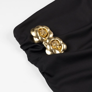 Detailaufnahme von 3D-Metallrosen-Schnallen auf plissiertem schwarzem Strickgewebe