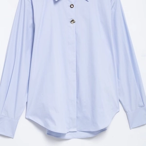 Chemise rayée femme bleu clair à manches longues avec boutons décoratifs et ourlet arrondi