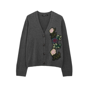 Détail d'un cardigan gris à col en V avec broderies roses colorées et maille texturée