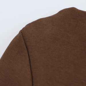 Detailed close-up of dark brown knit dress shoulder stitching and fine texture