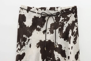 Détail de la jupe midi imprimé vache avec ceinture fine en cuir et embouts dorés
