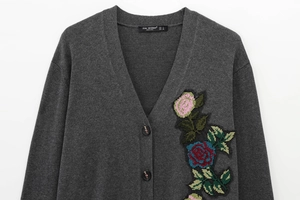 Détail de la broderie florale colorée sur un gilet en maille gris foncé pour femme