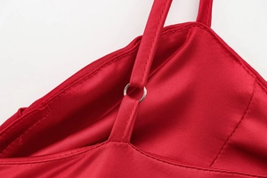 Détail d'une robe en satin rouge avec une fine bretelle et un anneau en métal argenté