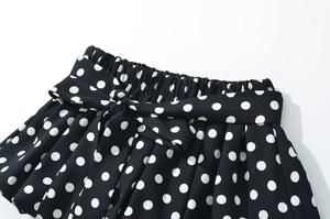 Detail of high-waist ruffled polka dot shorts with adjustable decorative bowtie knot