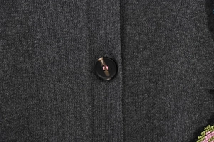 Gros plan sur la maille gris foncé avec bouton marbré et broderie florale colorée