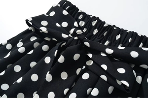 Close-up of elastic waistband with decorative bow on black polka dot ruffled shorts