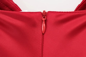 Détail de la fermeture éclair invisible sur une robe midi en satin rouge avec coutures fines